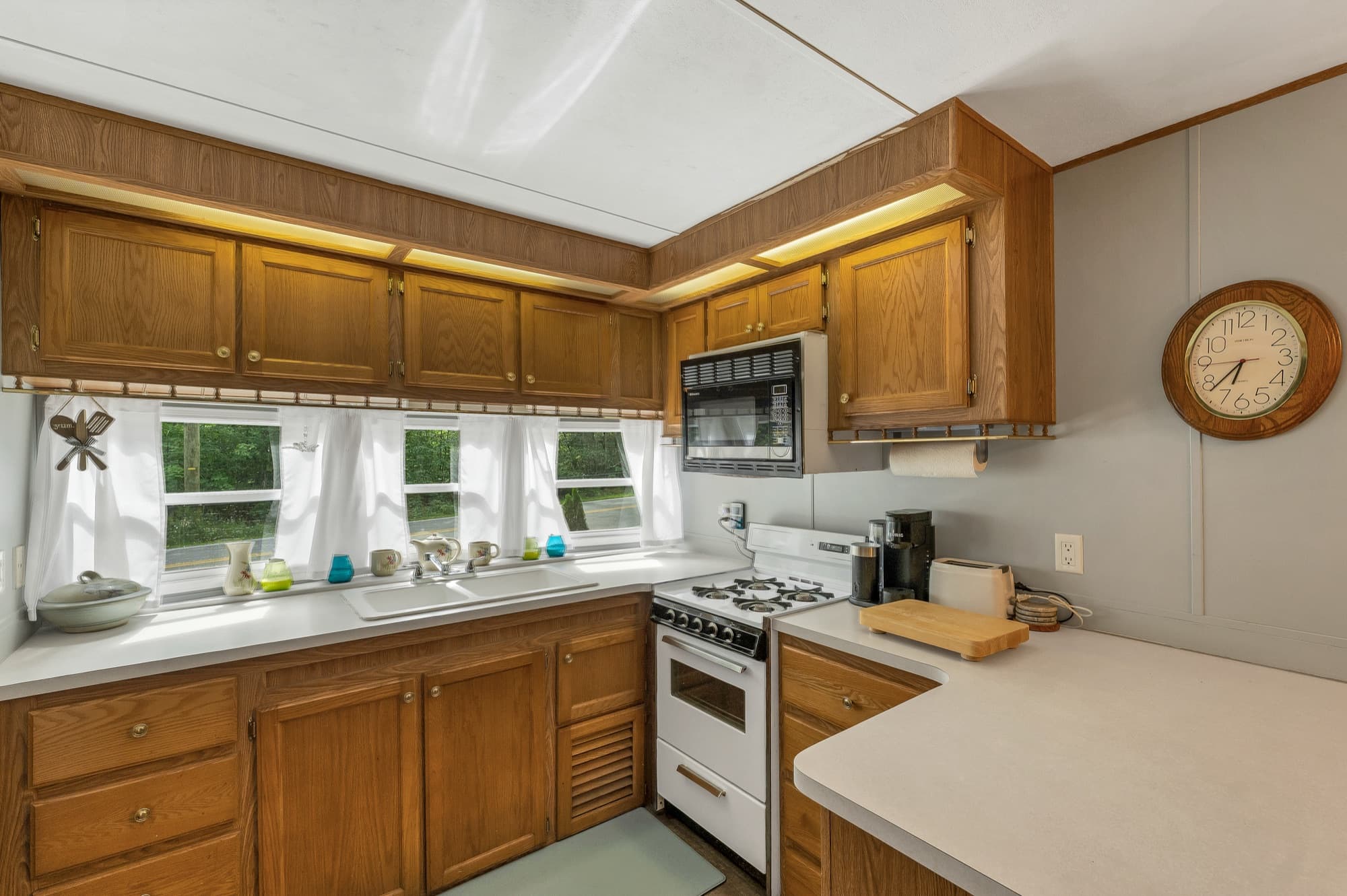 The kitchen with oak cabinets, a gas range, and windows over the sink