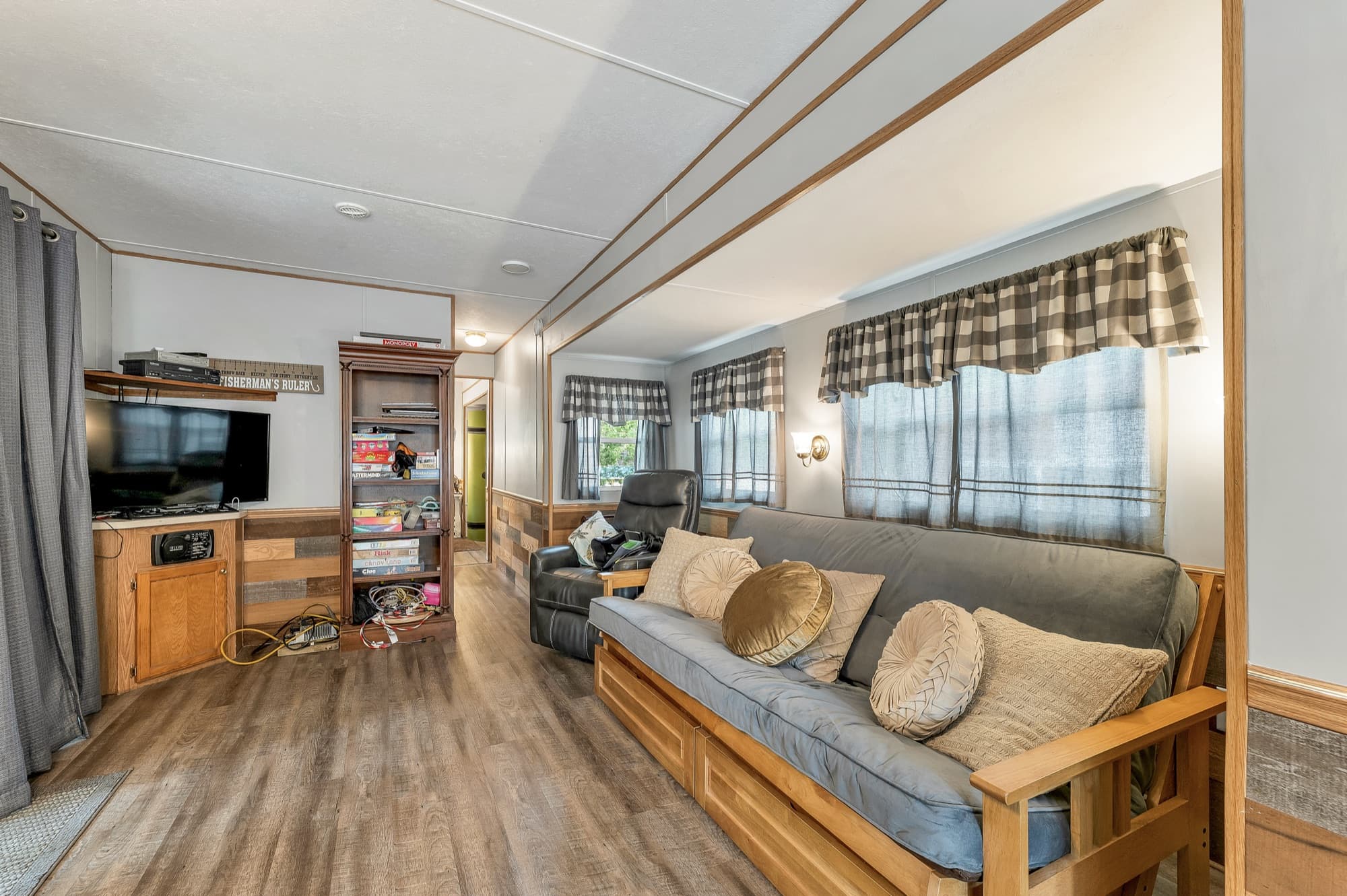 The living area with the futon, the television, and wood-look floors