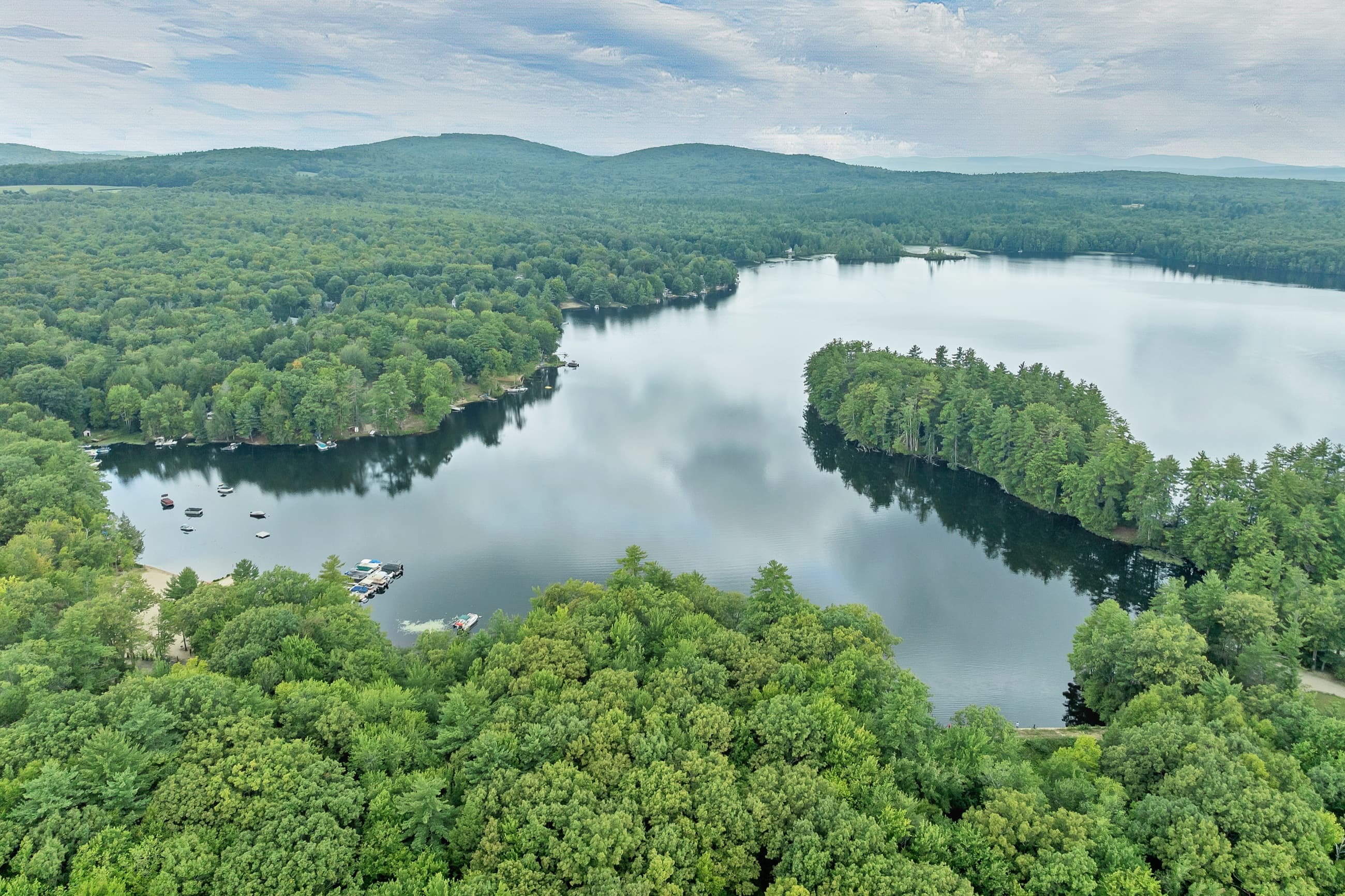Aerial view of Baxter Lake and its wooded shoreline under a cloudy summer sky
